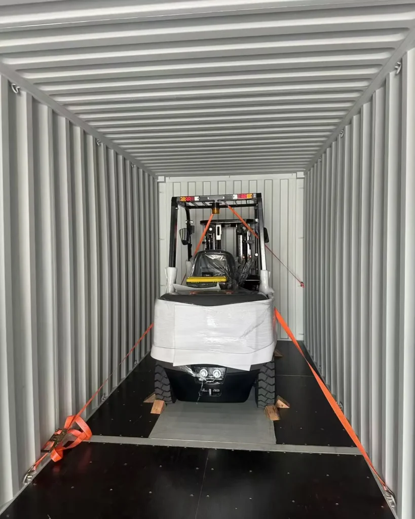 Forklift secured inside a 40ft container with wooden blocks and ratchet straps